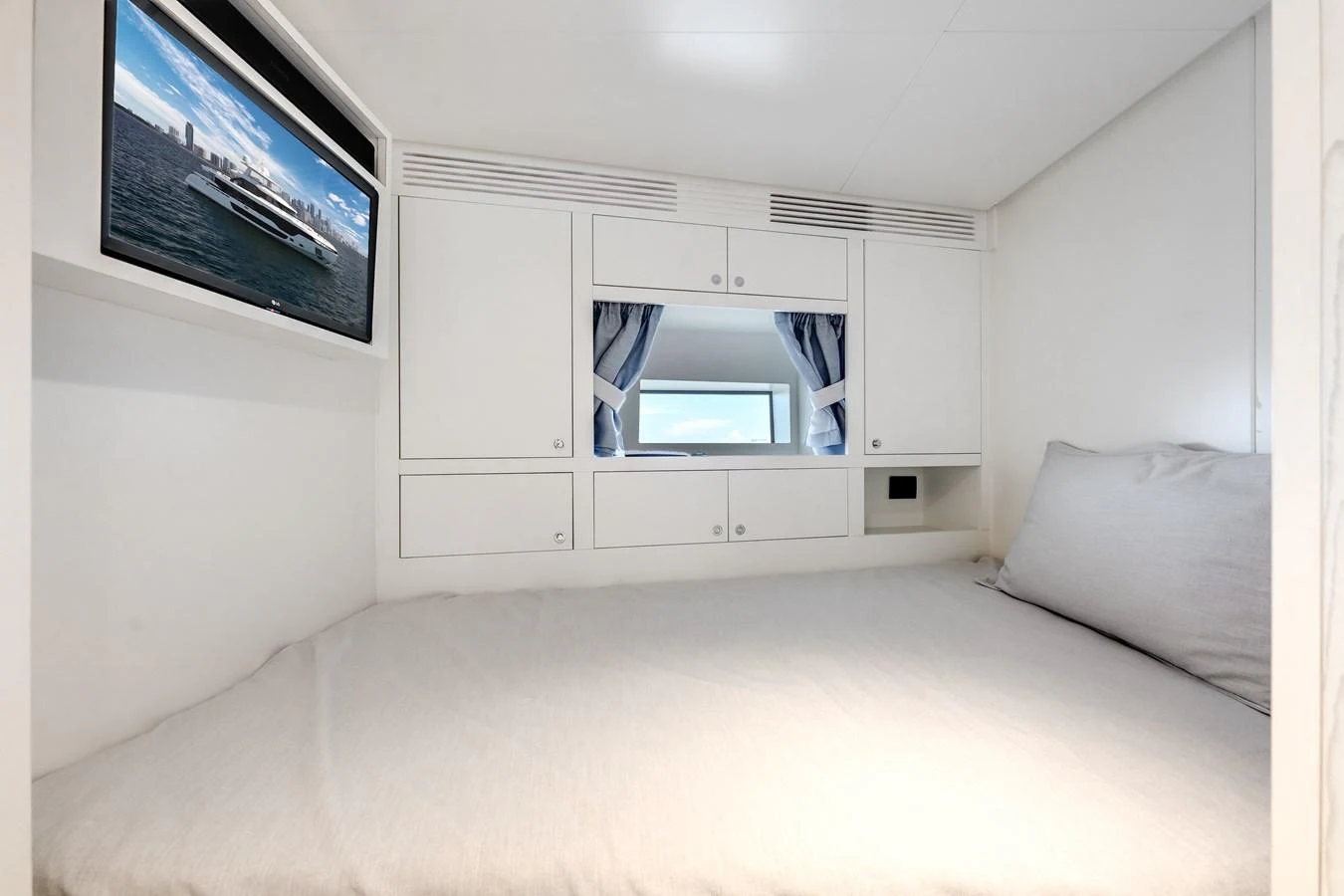 A cozy yacht cabin featuring a comfortable bed and a wall-mounted TV. aboard TYCOON Yacht for Sale