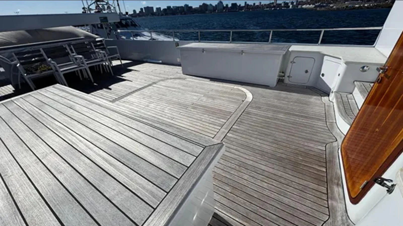 a deck with a boat and a deck with a large boat in the background aboard BELLE ISLE SEA Yacht for Sale