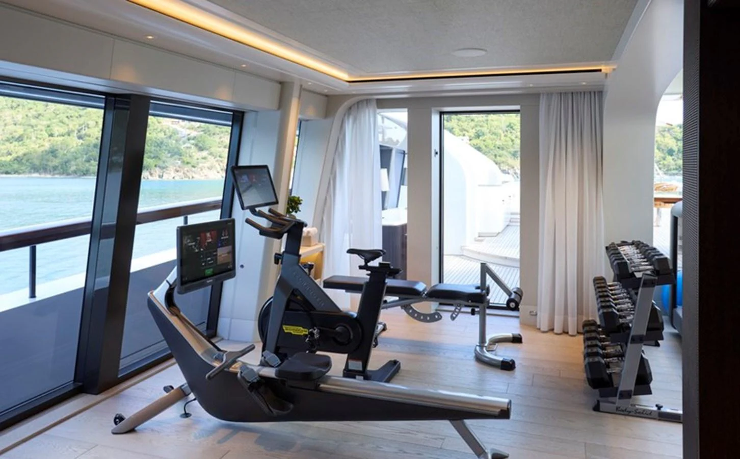 a room with a large window and a desk with treadmills aboard VANISH Yacht for Sale
