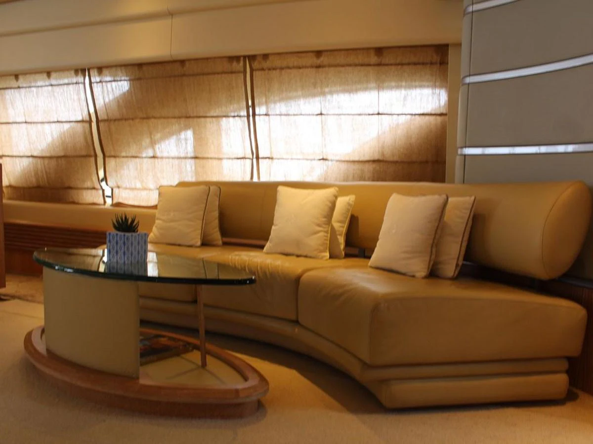 a couch with pillows and a coffee table in a room with windows aboard AZIMUT 98 LEONARDO Yacht for Sale