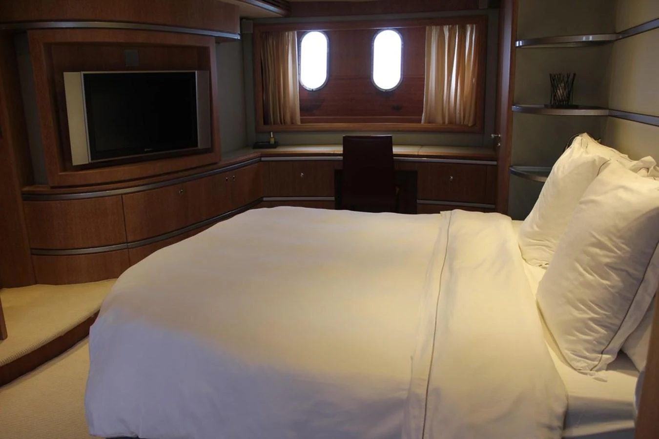 a bed with a white sheet and a television on the wall aboard AZIMUT 98 LEONARDO Yacht for Sale