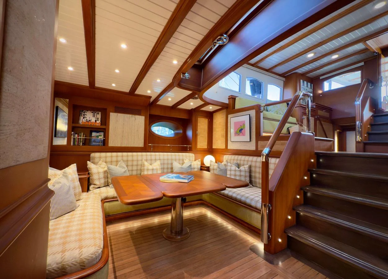 a room with a wood table and couches aboard NAMUUN Yacht for Sale