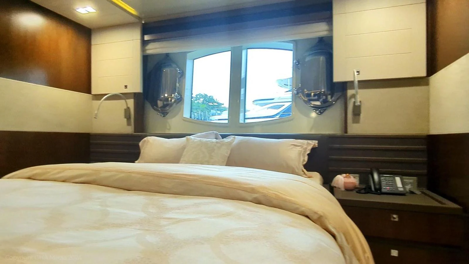 a bed with a white sheet and a white pillow in a room with a window and wood cabinets aboard OXYGEN Yacht for Sale