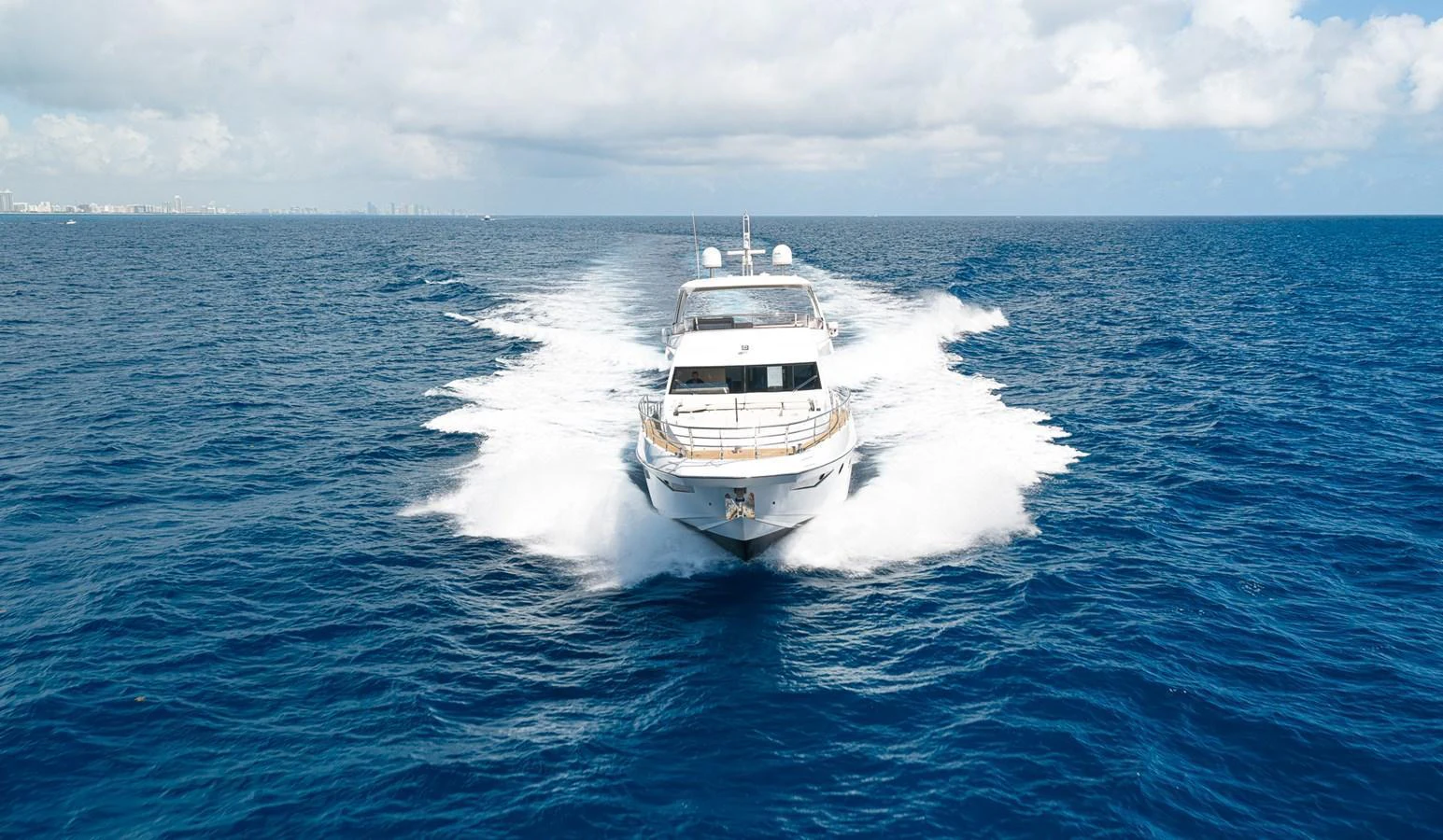 A luxurious yacht cruises swiftly through the open sea under a bright, clear sky. aboard SABI Yacht for Sale