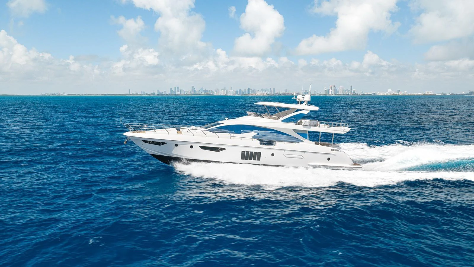 A sleek and modern yacht cruises swiftly on the open sea under a bright blue sky. aboard SABI Yacht for Sale