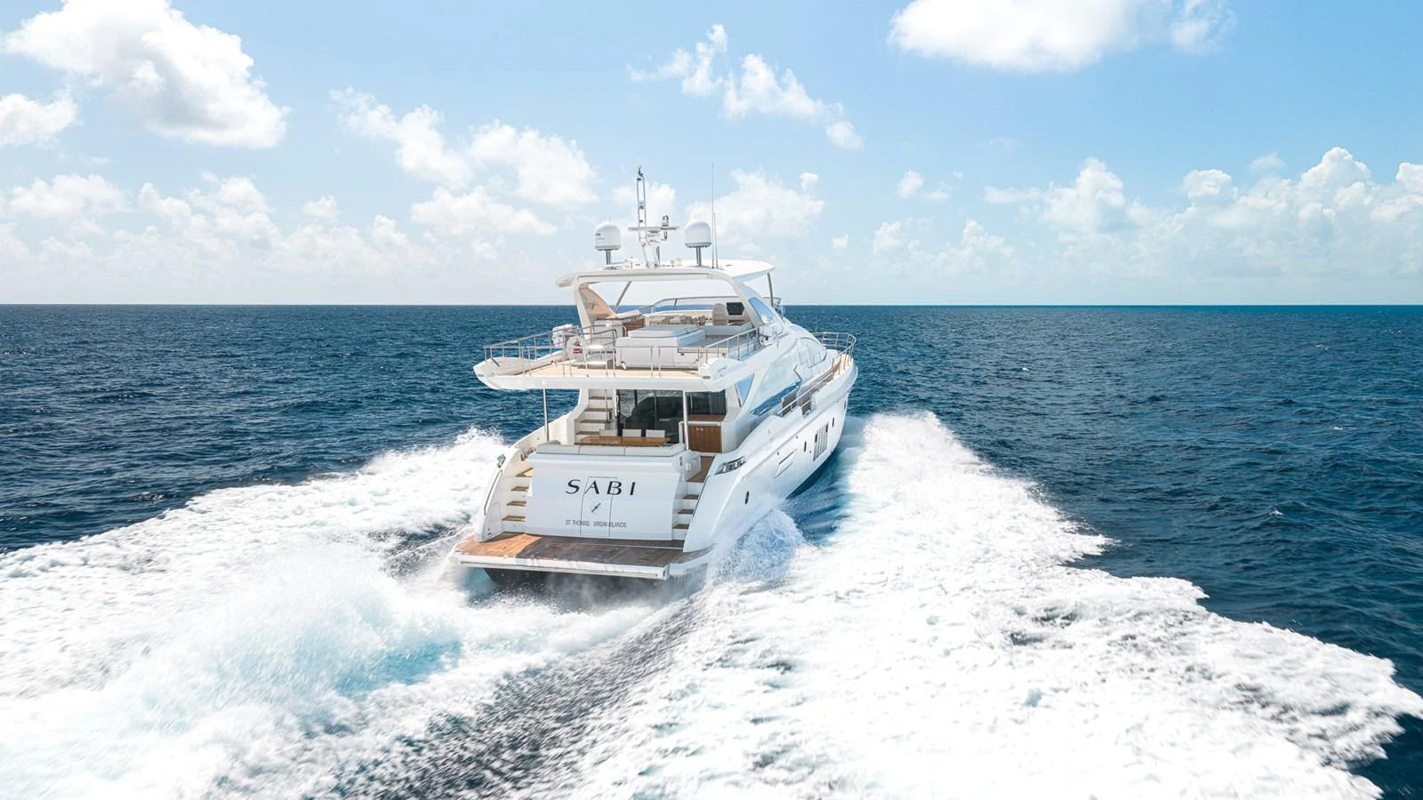 A luxurious yacht cruises through the open sea, leaving a trail of white foam behind. aboard SABI Yacht for Sale