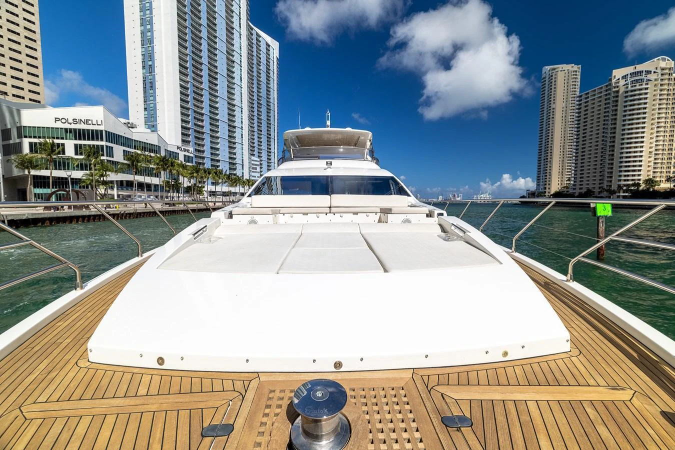 The yacht's foredeck offers a spacious sunbathing area with a stunning cityscape backdrop. aboard SABI Yacht for Sale