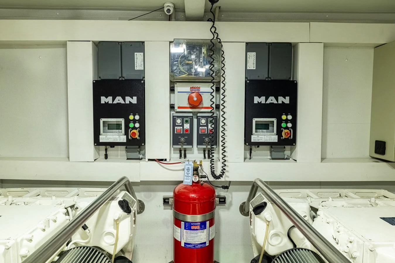 a red and white fire extinguisher on a white wall aboard SABI Yacht for Sale