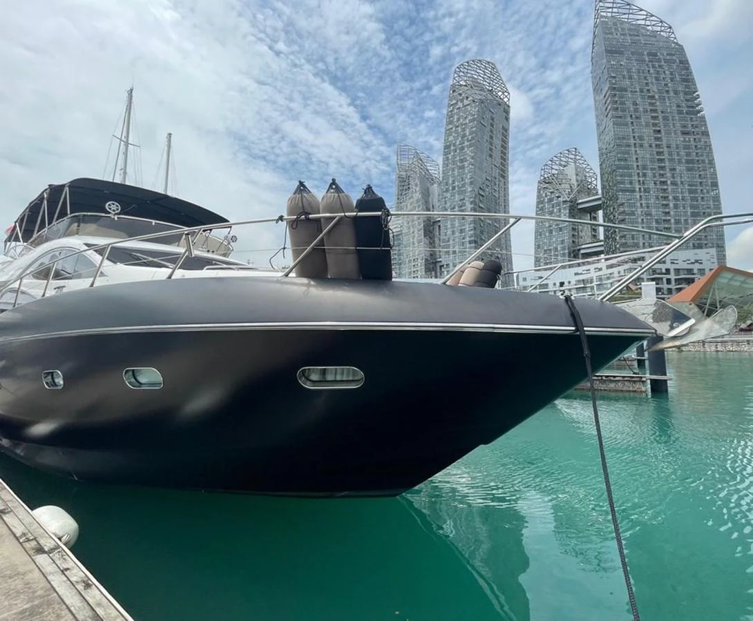 A sleek yacht is docked in a modern marina with striking architectural buildings in the background. aboard ELLYN Yacht for Sale