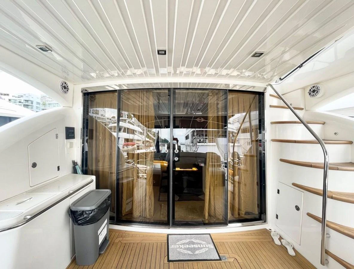The aft deck features a sliding glass door leading to the interior, with a staircase to the upper deck and a compact kitchenette area. aboard ELLYN Yacht for Sale