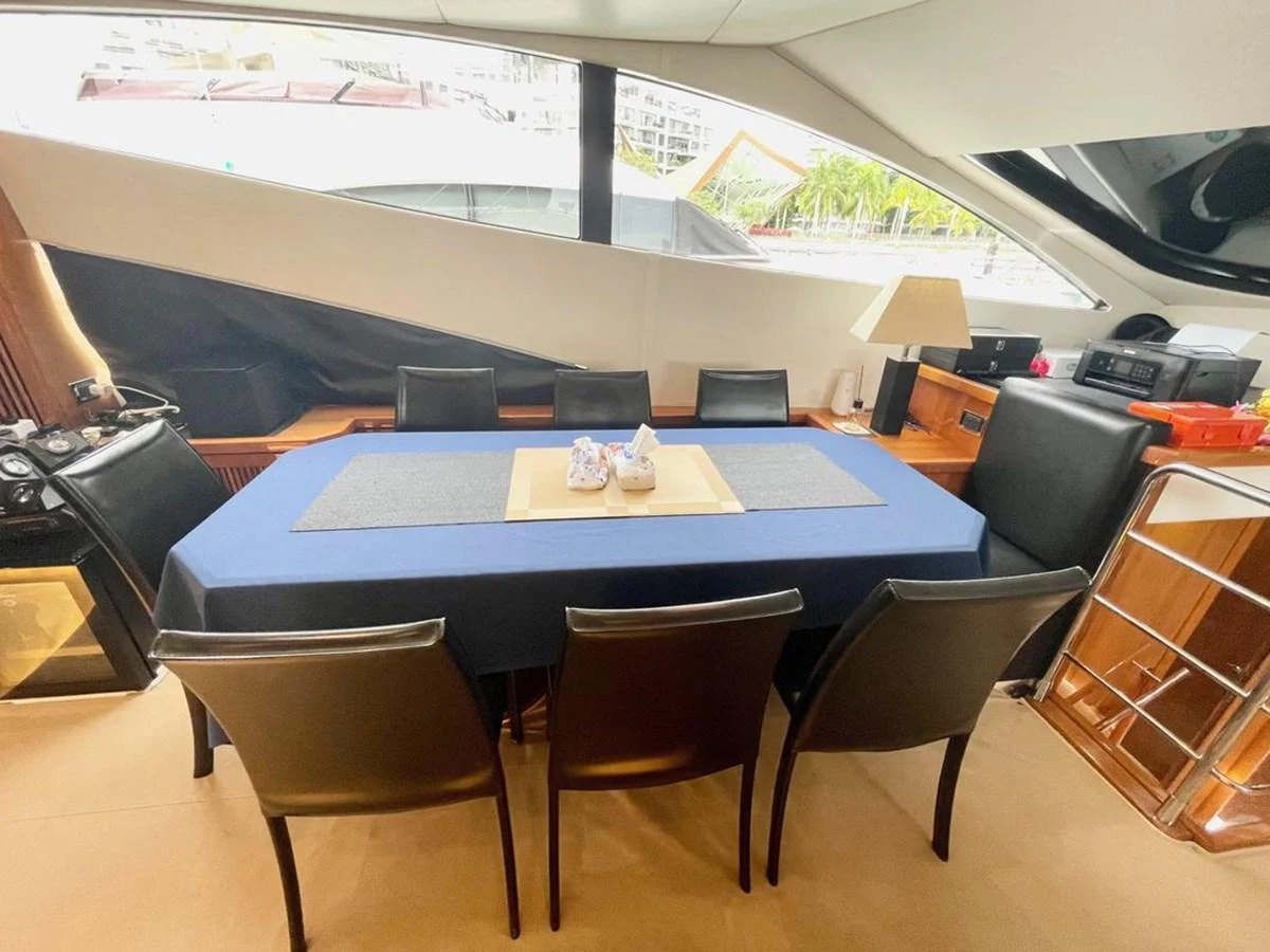 The yacht's dining area features a sleek table with comfortable seating and a view of the outside through large windows. aboard ELLYN Yacht for Sale