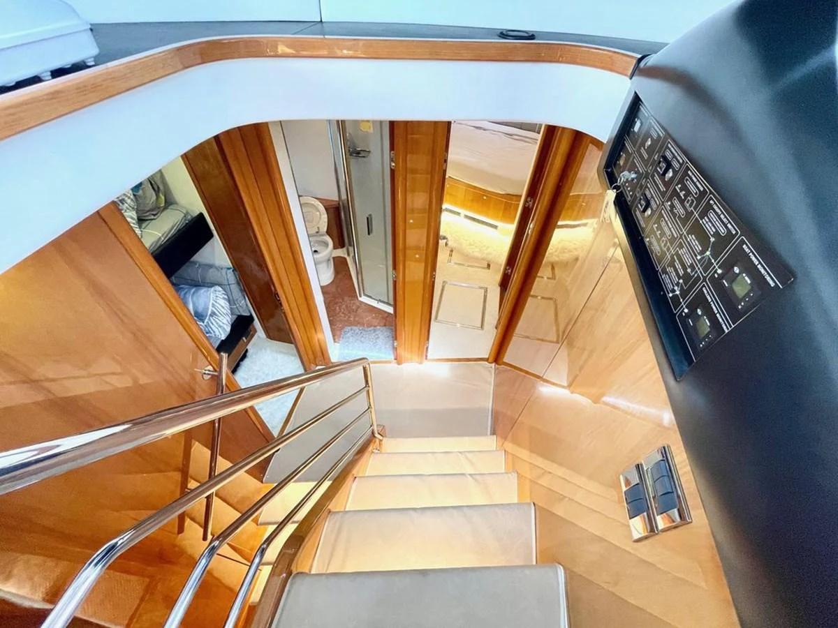 The image showcases a luxurious interior staircase with polished wood finishes and modern design elements. aboard ELLYN Yacht for Sale
