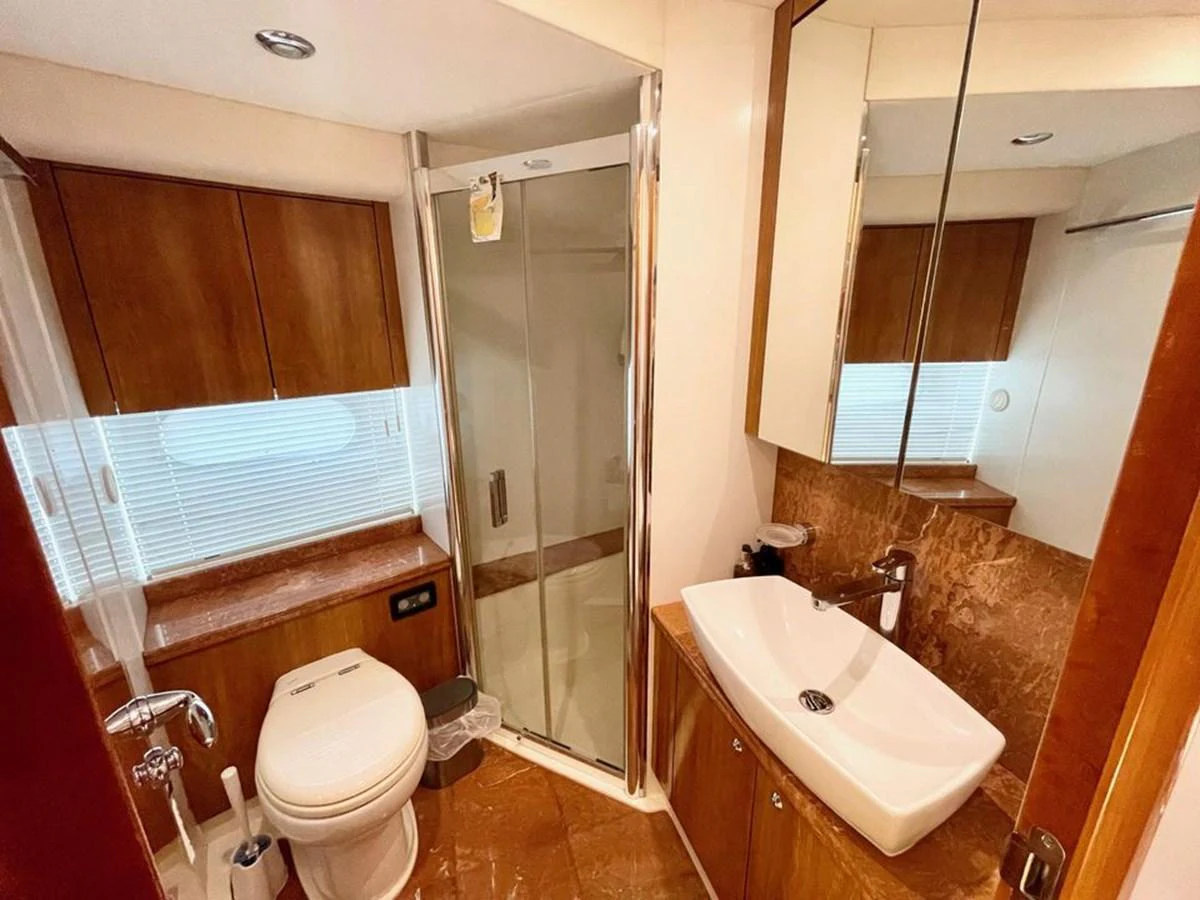The yacht's bathroom features a modern design with a glass-enclosed shower, sleek sink, and wooden cabinetry. aboard ELLYN Yacht for Sale
