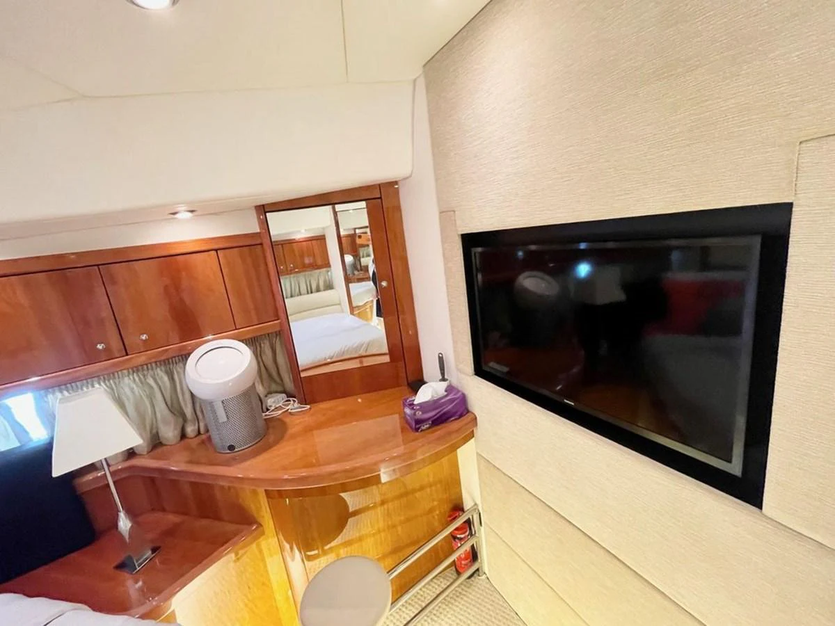 The stateroom features a flat-screen TV, wooden cabinetry, and a comfortable bed. aboard ELLYN Yacht for Sale