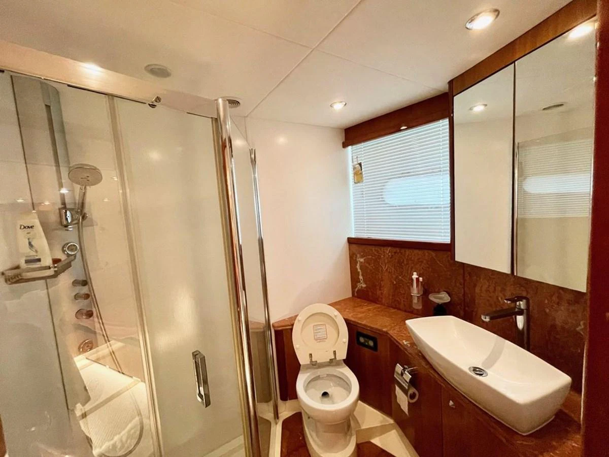 The yacht's bathroom features a modern shower, toilet, and sink with elegant wood accents. aboard ELLYN Yacht for Sale