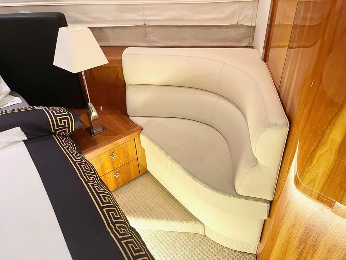 The image showcases a luxurious stateroom with a cozy seating area and elegant wooden finishes. aboard ELLYN Yacht for Sale