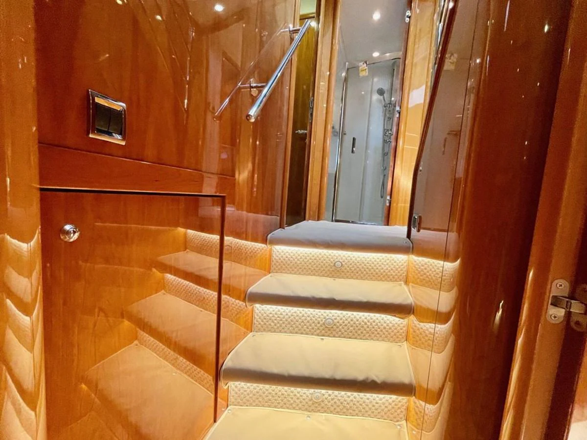 A polished wooden staircase with soft lighting leads to the upper level of the yacht. aboard ELLYN Yacht for Sale