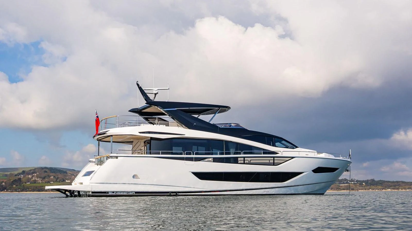 A sleek and modern yacht glides gracefully on calm waters under a partly cloudy sky. aboard SU Yacht for Sale