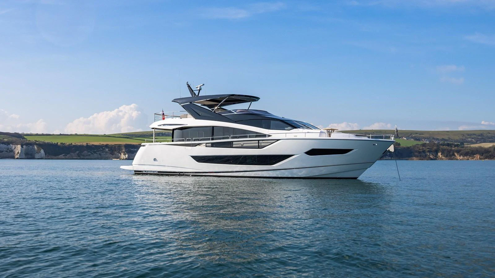 A sleek and modern yacht glides gracefully on calm waters against a scenic coastal backdrop. aboard SU Yacht for Sale