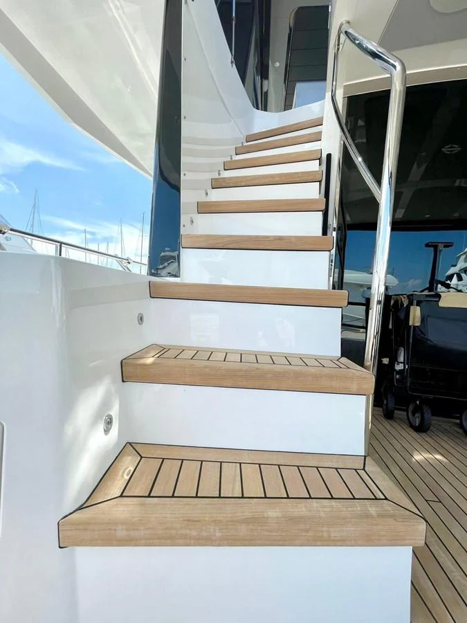 A sleek staircase with wooden steps leads to the upper deck of the yacht. aboard SU Yacht for Sale