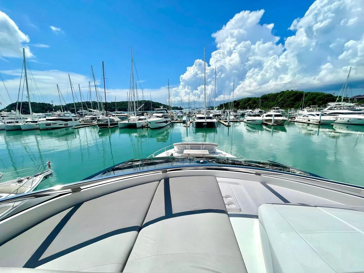 The yacht is docked in a serene marina, showcasing its spacious bow area under a bright blue sky. aboard SU Yacht for Sale