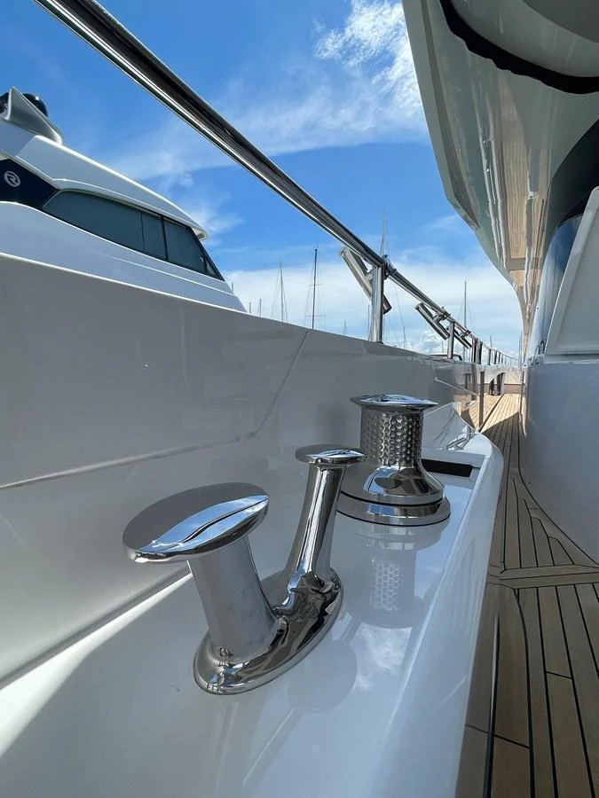 A close-up view of the yacht's deck hardware and polished fittings against a backdrop of clear skies and marina. aboard SU Yacht for Sale