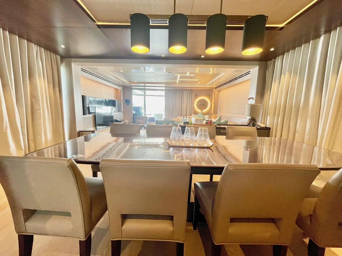 The yacht's dining area features a sleek table with comfortable seating and modern lighting. aboard SU Yacht for Sale