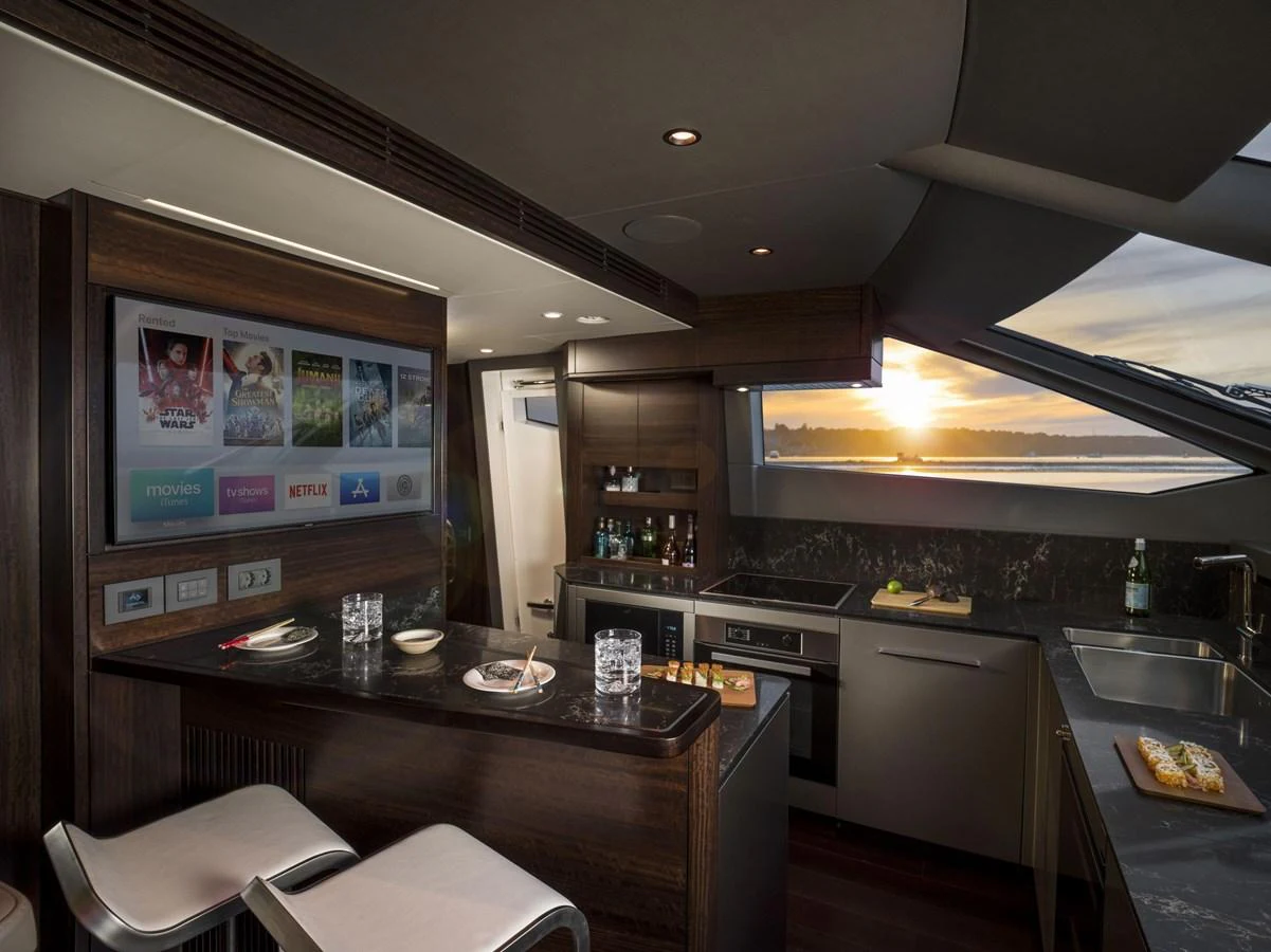 The galley features modern appliances, a sleek countertop, and a cozy dining area with a view of the sunset. aboard SU Yacht for Sale