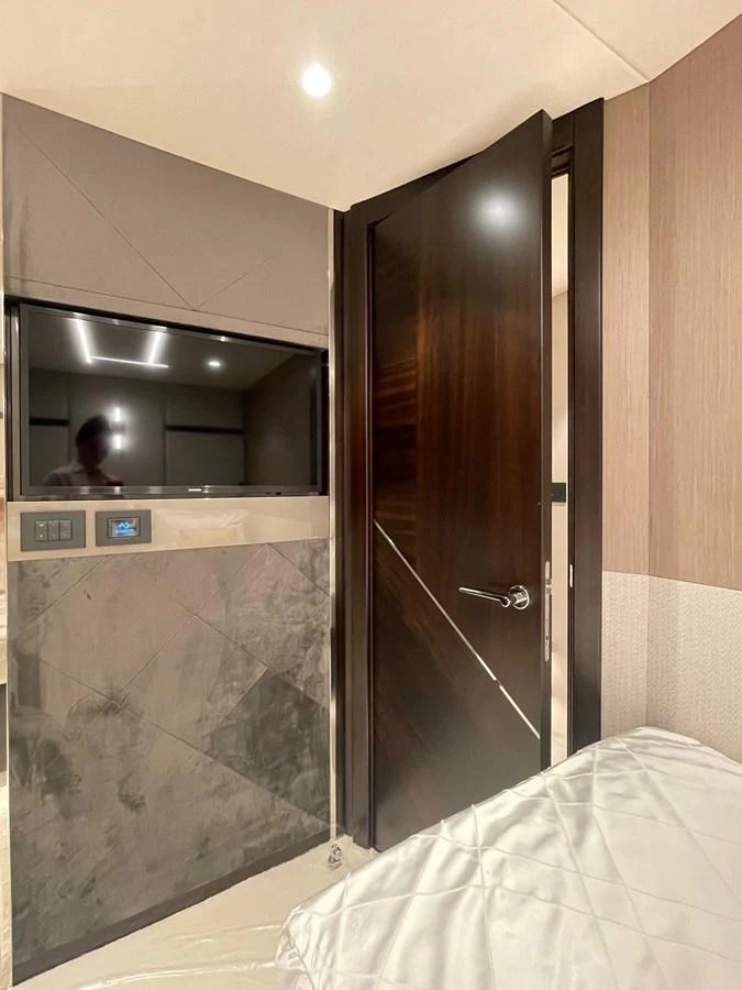 A luxurious stateroom featuring a sleek TV setup and a modern door design. aboard SU Yacht for Sale