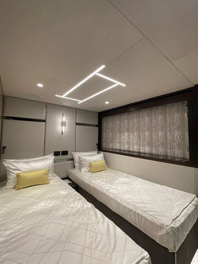 The guest stateroom features twin beds with modern lighting and a serene ambiance. aboard SU Yacht for Sale