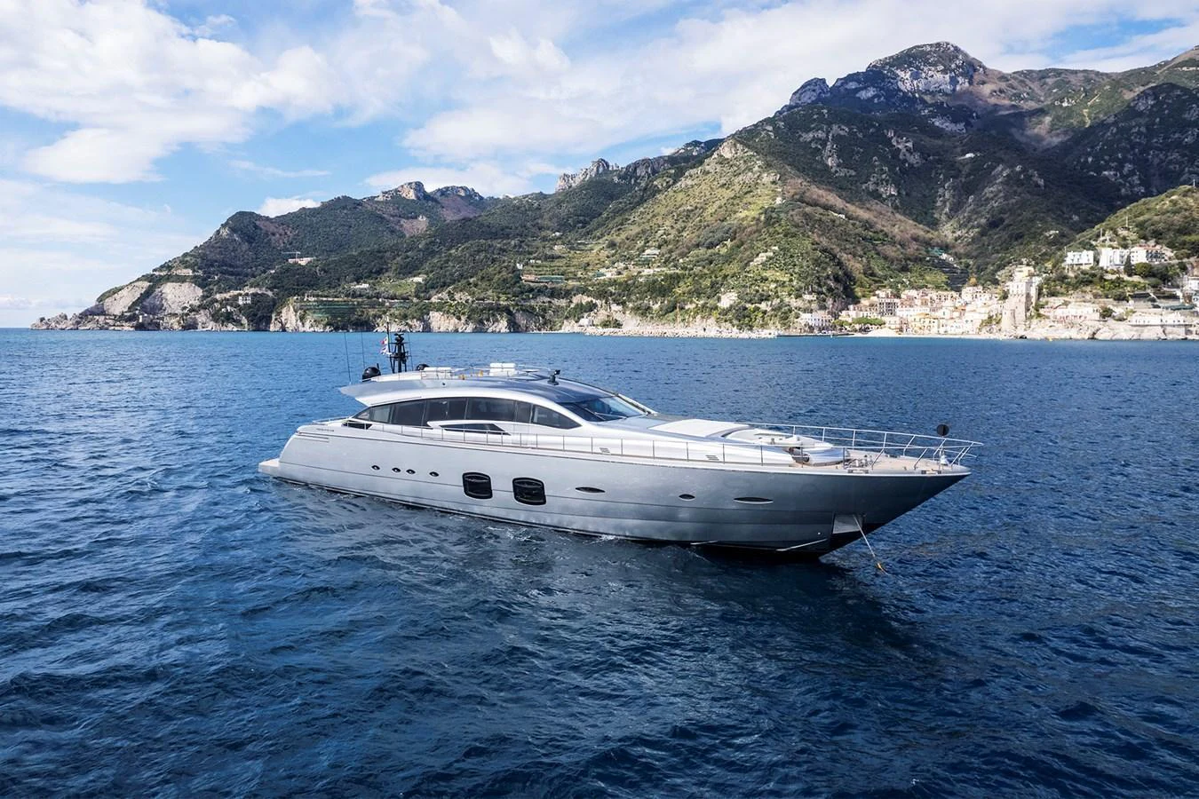 A sleek, modern yacht glides gracefully on calm blue waters with a stunning mountainous backdrop. aboard GRACE Yacht for Sale