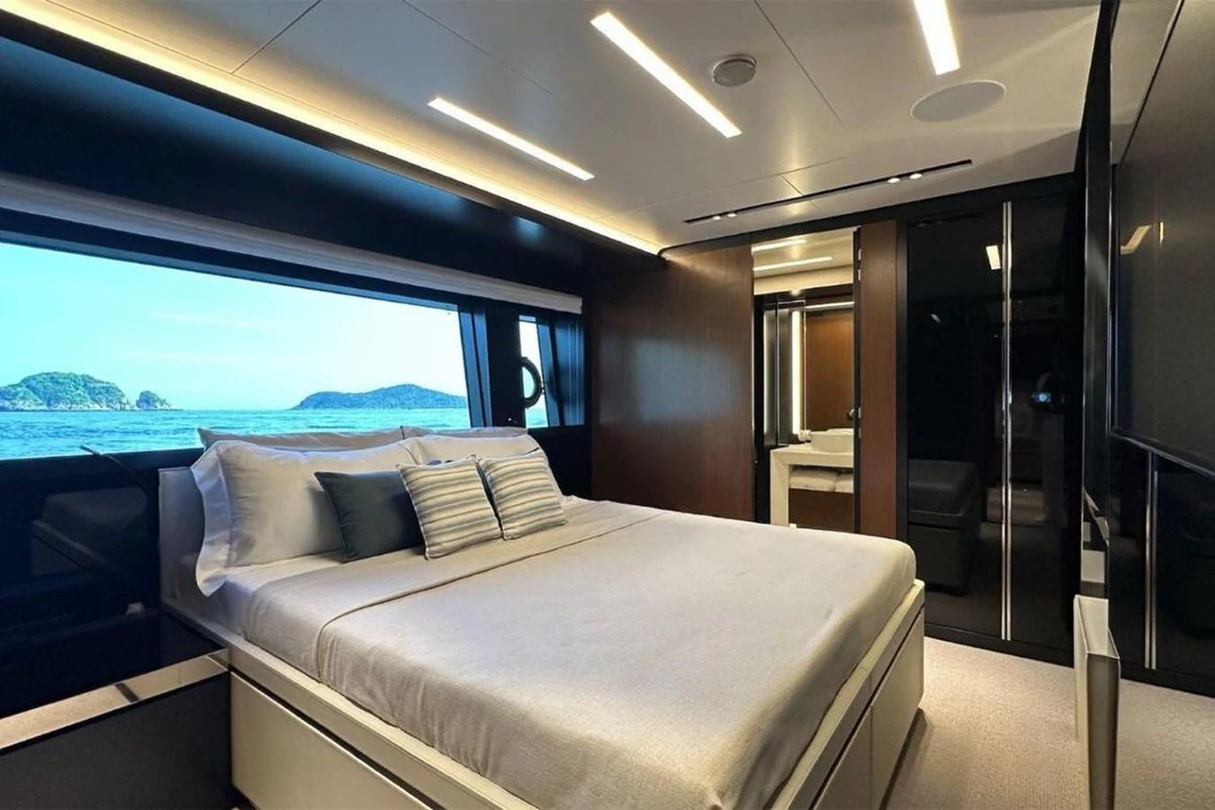 A luxurious stateroom with a large bed and scenic ocean view through the window. aboard BELLA DONNA Yacht for Sale