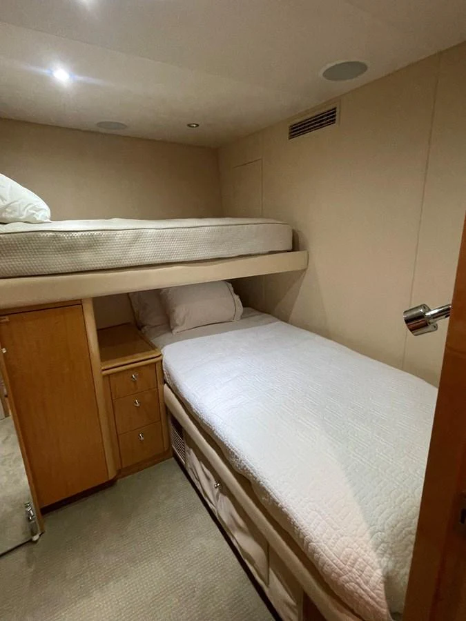 A cozy guest cabin with bunk beds and warm wooden cabinetry. aboard HOPE Yacht for Sale