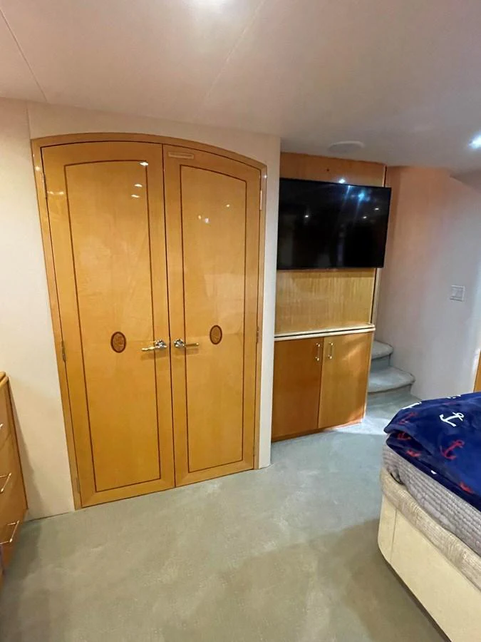 The stateroom features elegant wooden cabinetry, a flat-screen TV, and plush carpeting for a cozy retreat. aboard HOPE Yacht for Sale