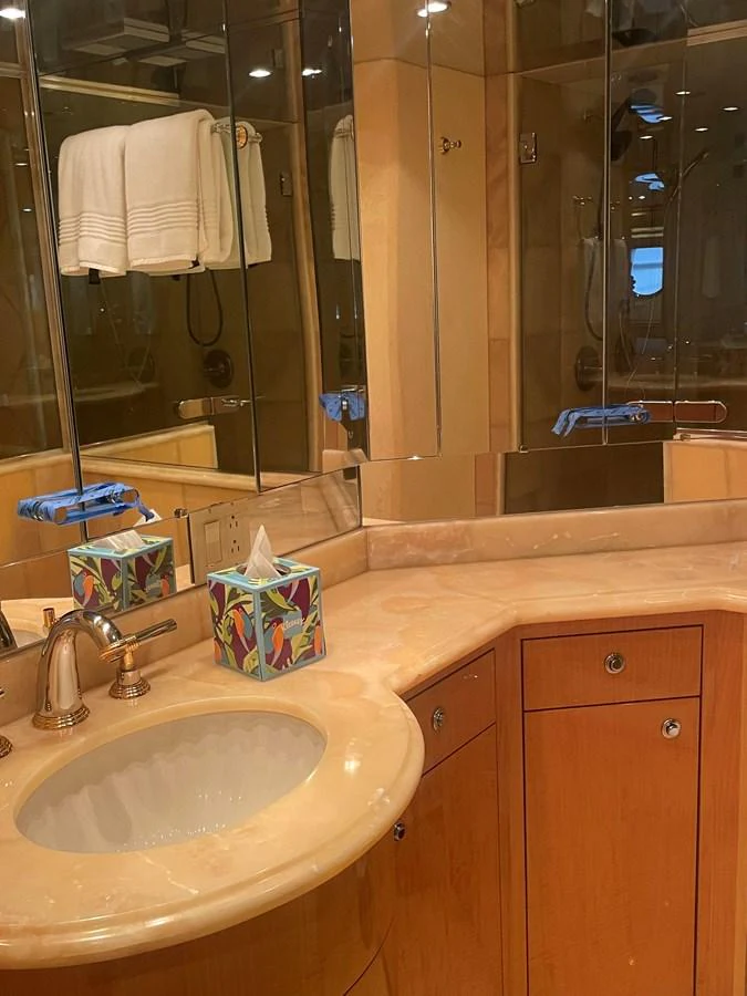 The yacht's bathroom features elegant wood cabinetry, a marble countertop, and mirrored walls for a luxurious touch. aboard HOPE Yacht for Sale