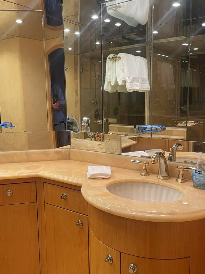 The yacht's bathroom features elegant wooden cabinetry, a polished countertop, and a well-lit mirror. aboard HOPE Yacht for Sale