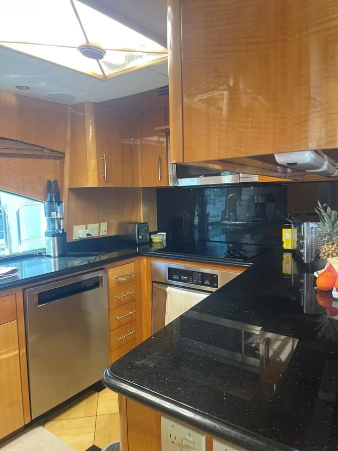 The yacht's galley features sleek wooden cabinetry, modern appliances, and a polished black countertop. aboard HOPE Yacht for Sale