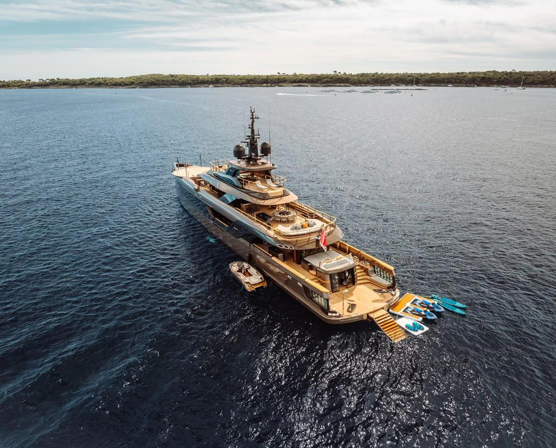 A luxurious yacht is anchored in serene blue waters, showcasing its expansive decks and water toys. aboard RAJA Yacht for Sale