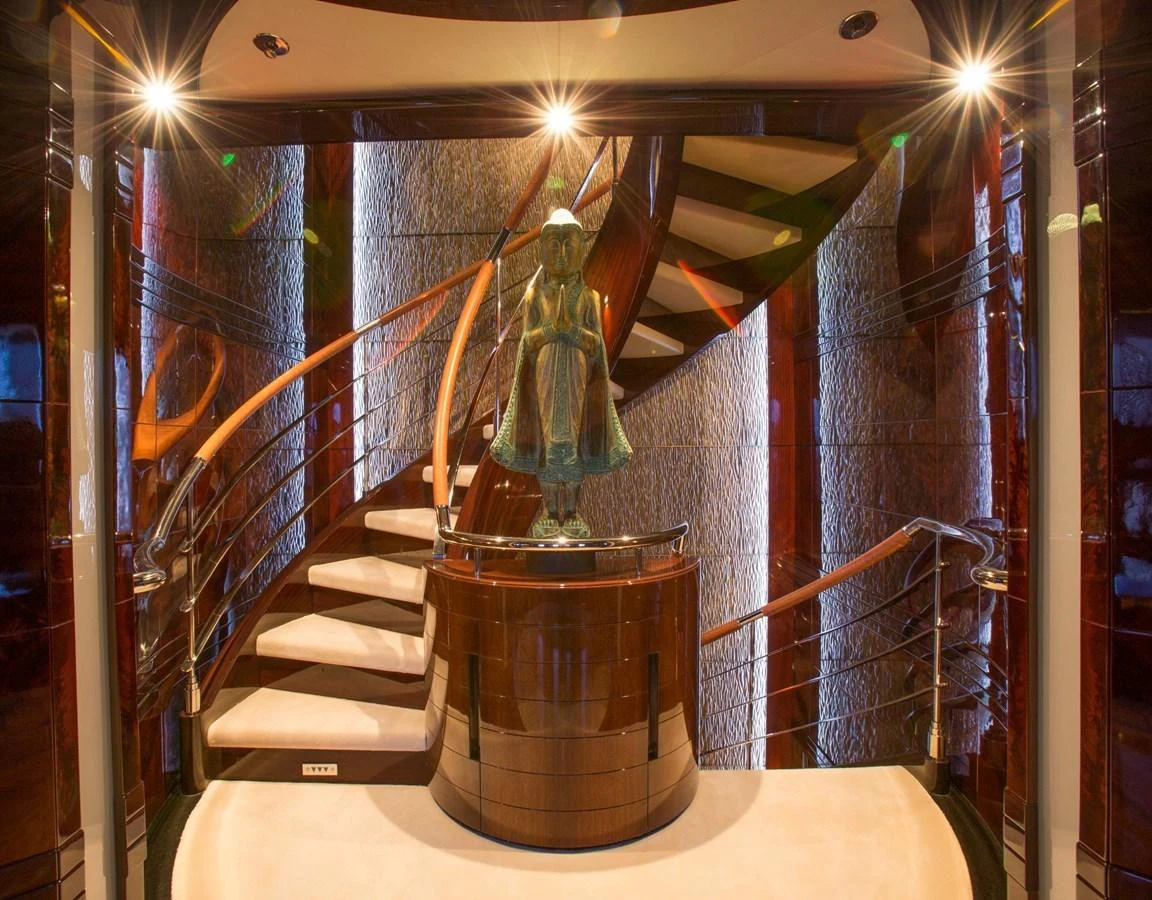 The yacht's interior features an elegant staircase with a striking sculpture centerpiece. aboard DREAM Yacht for Sale