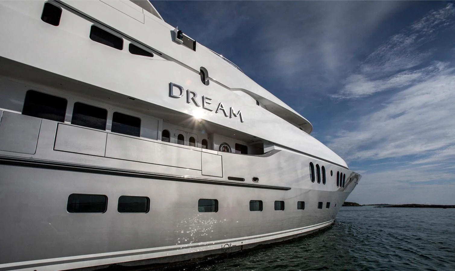 A sleek and modern yacht glides gracefully on the water under a clear sky. aboard DREAM Yacht for Sale