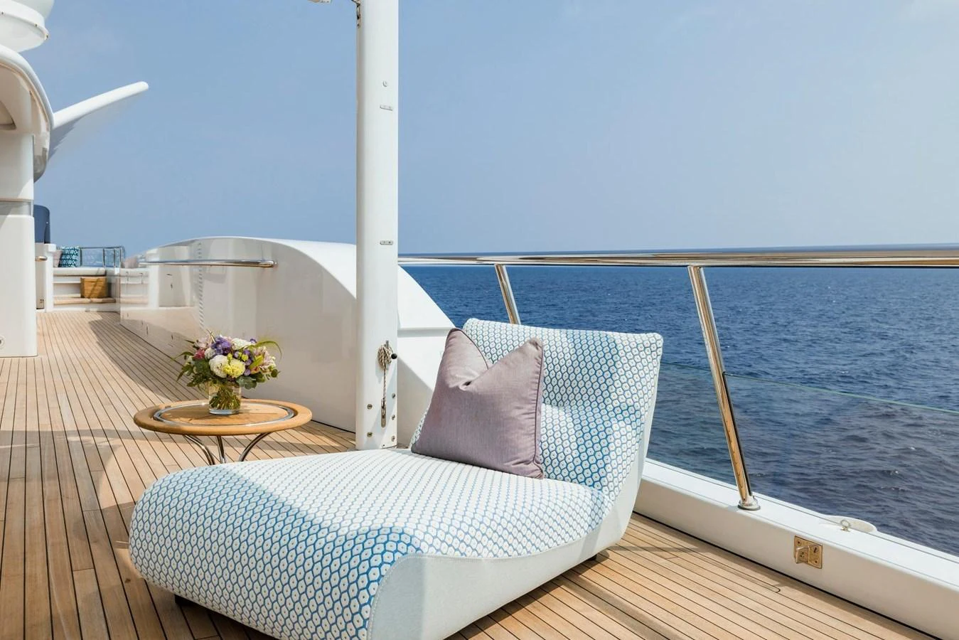 A serene deck area with a comfortable lounge chair and a small table overlooking the ocean. aboard DREAM Yacht for Sale