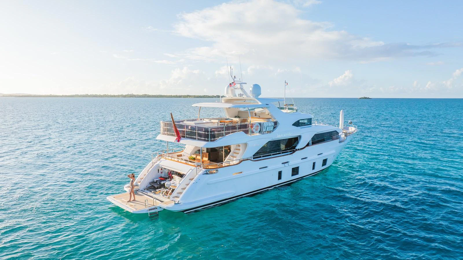 This luxurious yacht is anchored in serene blue waters, showcasing its elegant aft deck and spacious outdoor areas. aboard SEA GYPSY Yacht for Sale