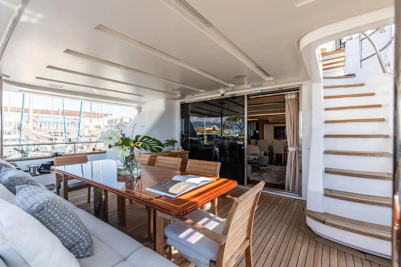 The aft deck features a stylish dining area with a polished wooden table and comfortable seating, perfect for al fresco meals. aboard SEA GYPSY Yacht for Sale