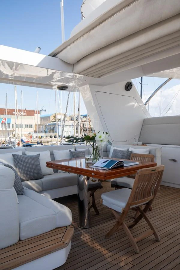 The aft deck offers a comfortable seating area with a wooden table, perfect for alfresco dining and relaxation. aboard SEA GYPSY Yacht for Sale