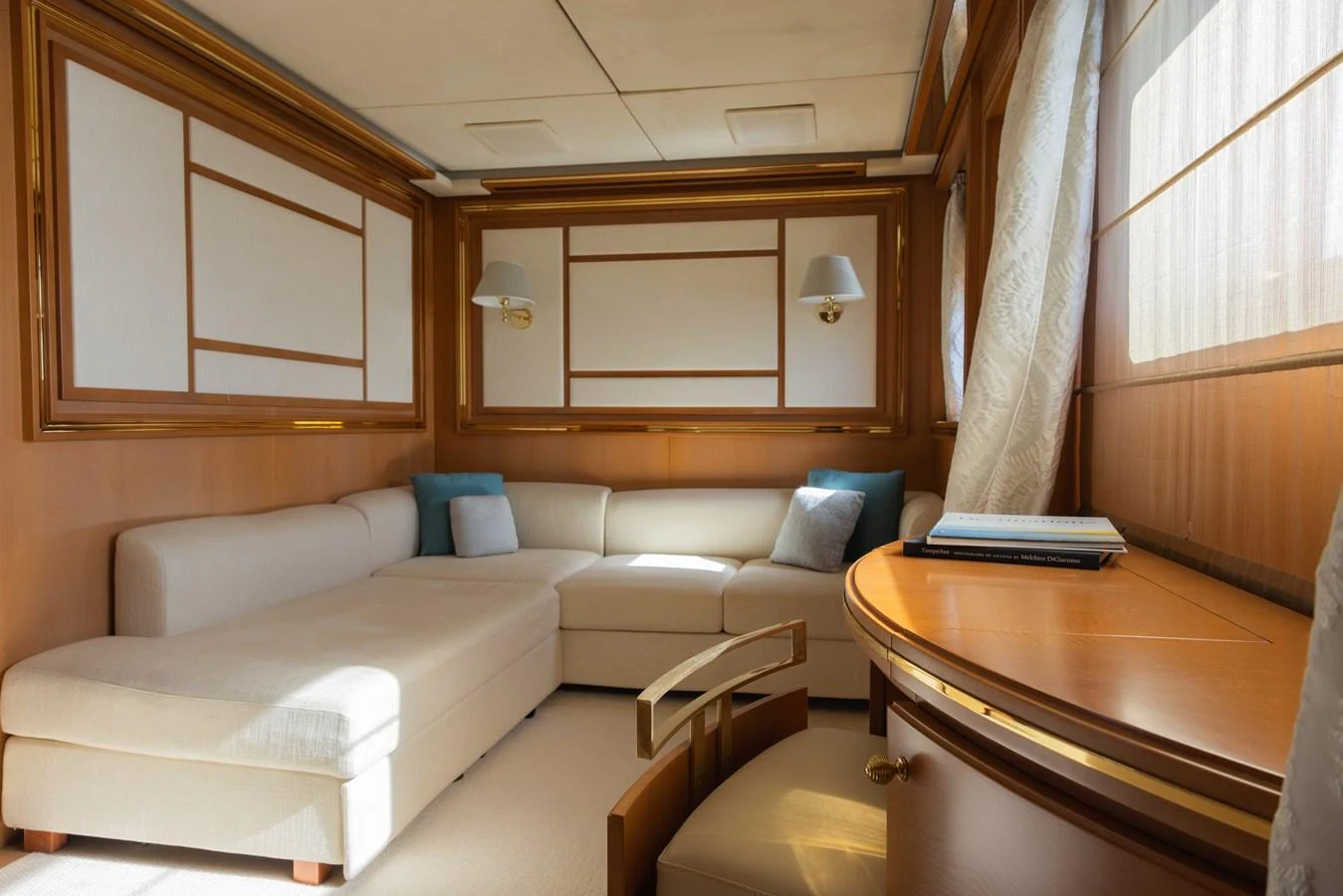 The yacht's lounge area features a plush L-shaped sofa with elegant decor and ample natural light. aboard SEA GYPSY Yacht for Sale