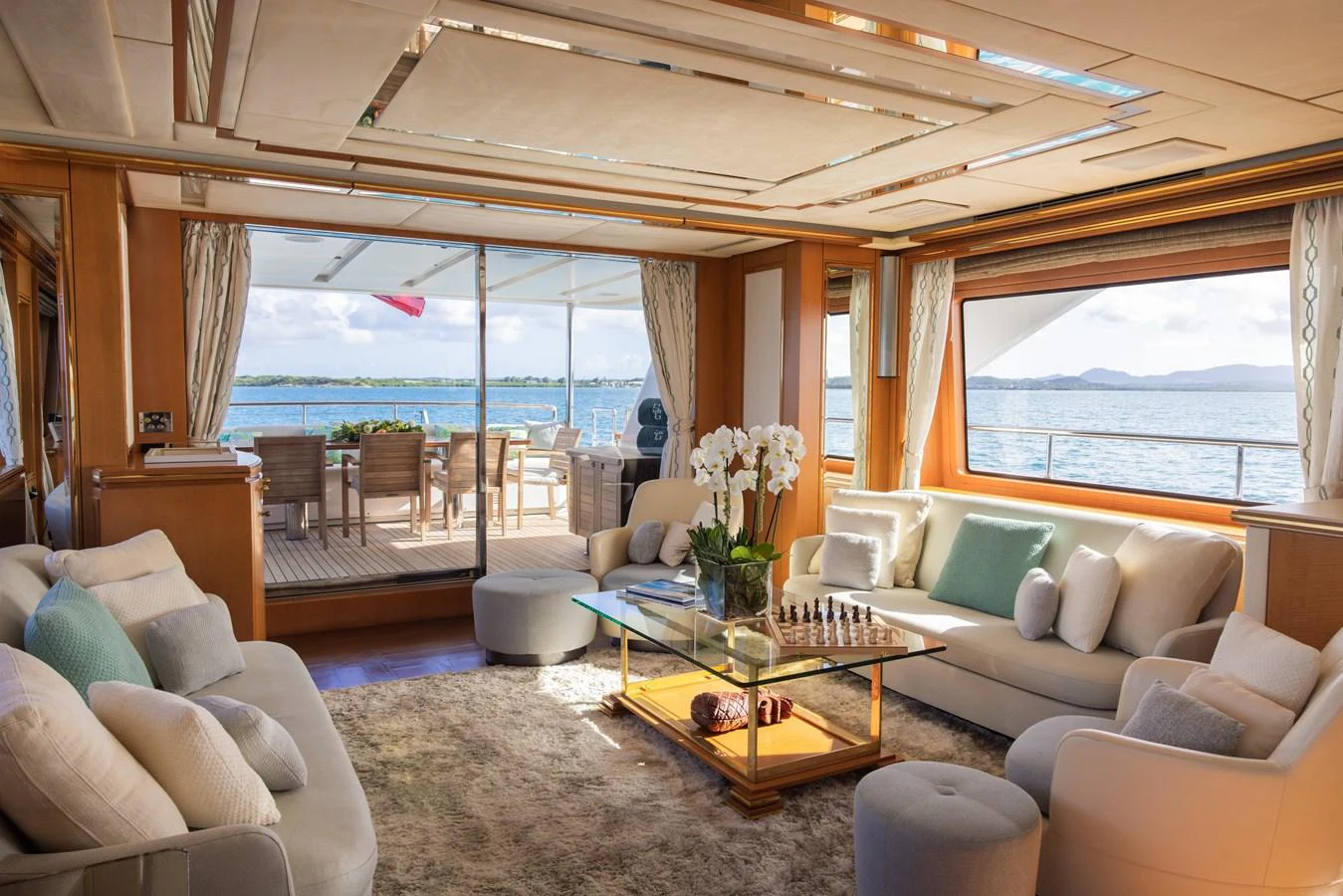 The yacht's salon offers a luxurious and comfortable space with plush seating, a glass coffee table, and expansive views of the sea. aboard SEA GYPSY Yacht for Sale