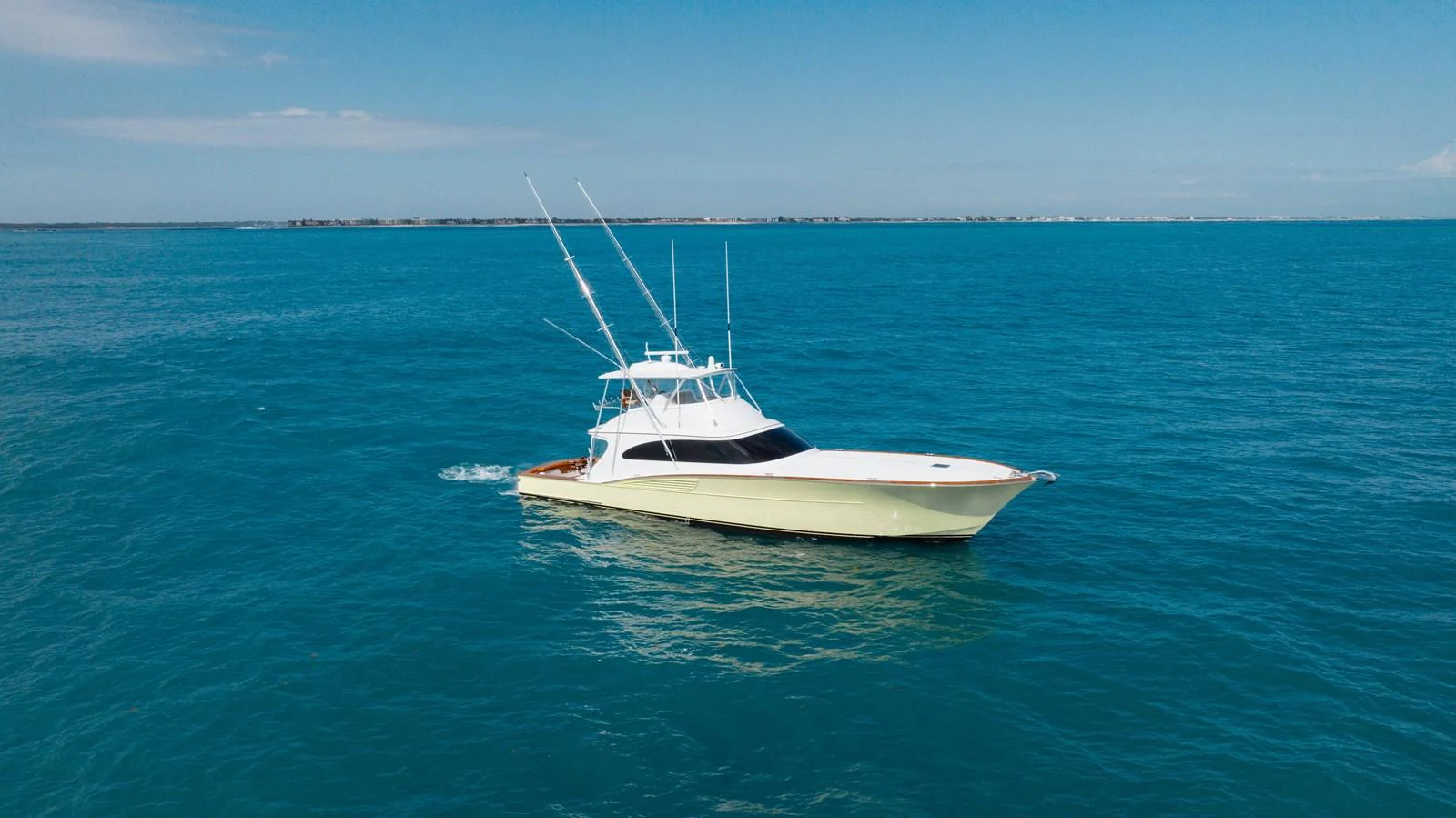 A sleek yacht cruises through calm, blue waters under a clear sky. aboard QUEEN BEE Yacht for Sale