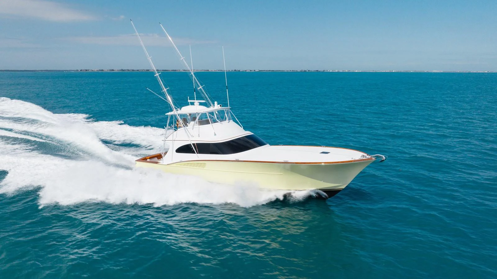 A sleek yacht cruises swiftly across the clear blue waters under a bright sky. aboard QUEEN BEE Yacht for Sale