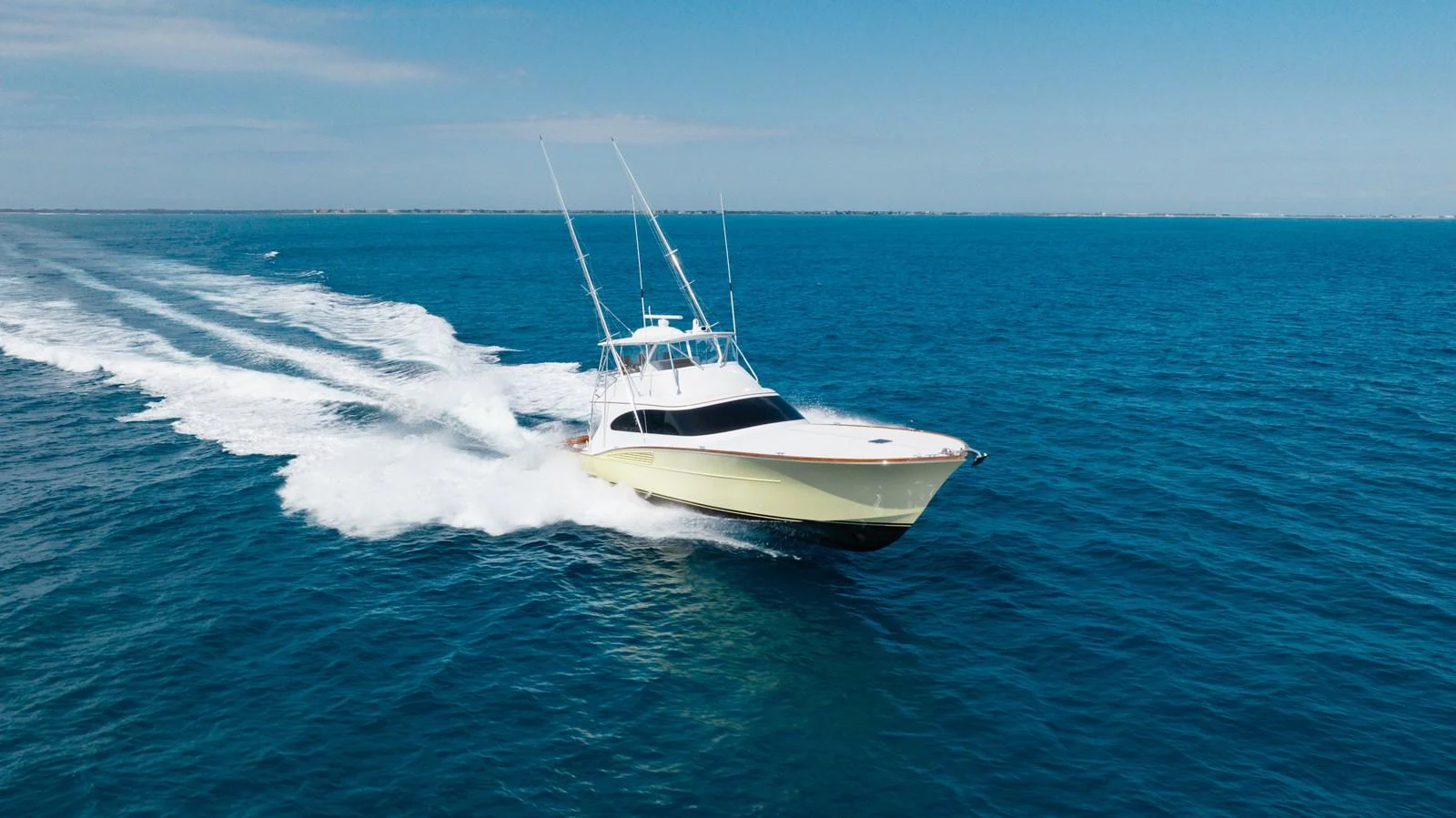 A sleek yacht cruises swiftly across the open ocean under a clear blue sky. aboard QUEEN BEE Yacht for Sale