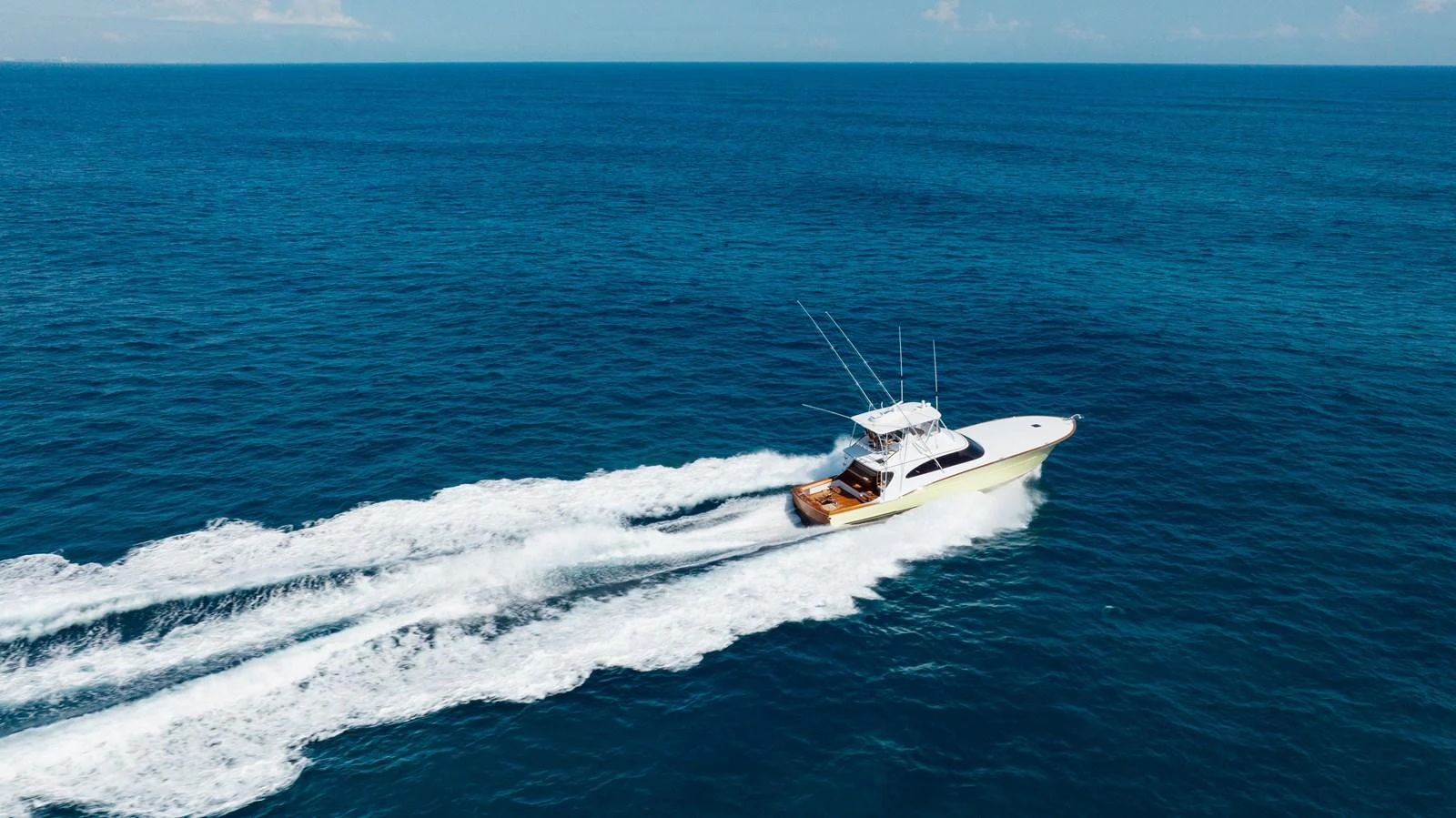 A sleek yacht cruises swiftly through the open ocean, leaving a trail of white wake behind. aboard QUEEN BEE Yacht for Sale